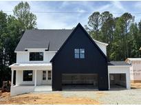 Striking two-story home showcasing a modern farmhouse design with a bold black garage and complementary white siding at 2391 Herbert Akins Rd, Fuquay Varina, NC 27526