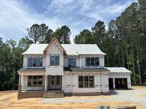 Under-construction two-story home with attached two-car garage against wooded backdrop at 2395 Herbert Akins Rd, Fuquay Varina, NC 27526