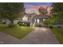 Charming two-story home with a well-maintained front yard and a concrete driveway at sunset at 6927 Beaverwood Dr Dr, Raleigh, NC 27616