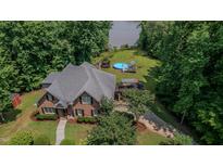 Stunning aerial view of brick home, pool and backyard near a serene lake at 7483 Danford Rd, Burlington, NC 27215