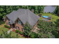 Aerial view of a brick home with a pool, trampoline, and access to a lake at 7483 Danford Rd, Burlington, NC 27215