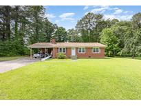 Charming brick ranch home with a lush green lawn and a covered carport for convenient parking at 9751 N Highway 96, Selma, NC 27576