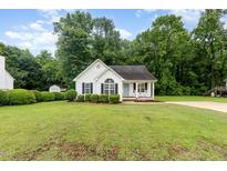 Charming one-story home featuring white siding, black shutters, manicured lawn, and well-maintained landscaping at 110 Oak Park Dr, Benson, NC 27504