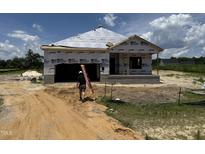 New construction of a single-Gathering home with builder carrying a ladder in the front of the house at 136 Tuskeegee Dr, Smithfield, NC 27577