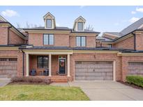 Charming brick townhouse featuring a two-car garage and welcoming front porch seating at 137 Cofield Cir, Durham, NC 27707