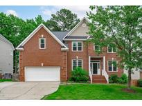 Charming brick home with an attached garage, well-maintained lawn and beautiful landscape at 2003 Red Sage Ct, Apex, NC 27502