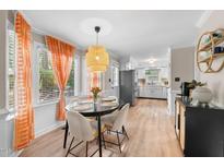 Bright dining area featuring a round table, woven pendant light, and large windows with vibrant orange curtains at 3541 E Jameson Rd, Raleigh, NC 27604