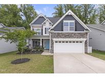 Charming two-story home with stone accents, a two-car garage, a blue front door, and mature landscaping at 4001 Bostwyck Dr, Fuquay Varina, NC 27526
