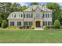 Stately two-story home with a brick facade, manicured lawn, black shutters, and charming dormer windows at 5112 Highbury Grove Ln, Fuquay Varina, NC 27526