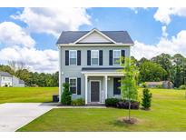 Charming two-story home features a light gray exterior, black shutters, and well-manicured front lawn at 60 Waterwheel Dr, Selma, NC 27576