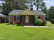 Charming brick home with black shutters, a cozy front porch, and lush green lawn at 905 S 1St St, Smithfield, NC 27577