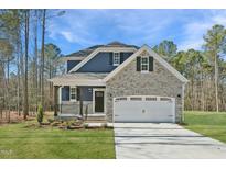 Charming two-story home featuring stone accents, a covered porch, and a two-car garage at Lot 4 Magnolia Acres Ln, Fuquay Varina, NC 27526