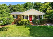 Charming brick home featuring a well-manicured lawn, red door, and inviting front porch at 1008 Mockingbird Dr, Raleigh, NC 27615