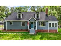 Charming home featuring dormer windows, a brick foundation, manicured lawn and inviting covered front entrance at 1052 Hughes Trl, Elon, NC 27244