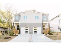 Charming two-story duplex with modern gray siding, white garage doors, and inviting wood stairs at 107 S Plum St, Durham, NC 27703