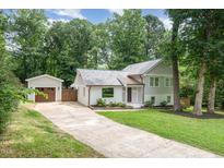 Charming home with a driveway leading to a detached garage, nestled amongst mature trees at 1209 Lanark Ct, Cary, NC 27511