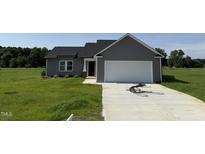 Charming single-story home featuring gray siding and a two-car garage on a green lot at 166 Coharie Dr, Lillington, NC 27546