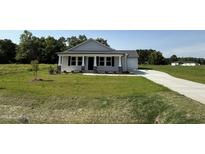 Charming single-story home with a well-manicured lawn and a covered front porch at 206 Coharie Dr, Lillington, NC 27546