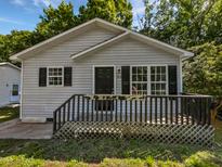 Charming single-story home featuring a cozy front porch and neutral siding, nestled among mature trees at 216 E Hinton St, Clayton, NC 27520