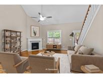 Bright living room featuring a fireplace, ceiling fan, hardwood floors, and large windows at 240 Paddy Ln, Youngsville, NC 27596