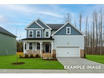 Charming two-story home with a manicured lawn, a welcoming porch, and a two-car garage at 412 Longleaf Glen Lane, Zebulon, NC 27597