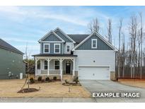 Charming two-story home featuring a welcoming front porch and a two-car garage, set against a backdrop of mature trees at 412 Longleaf Glen Lane, Zebulon, NC 27597
