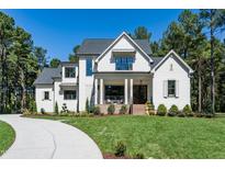 Beautiful two-story white home with a well-manicured lawn and lush landscaping on a sunny day at 476 Mollie Meadow Dr, Zebulon, NC 27597