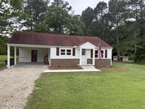 Charming one-story home with a red roof, patriotic accents, and a spacious front yard at 6300 Nc 27, Coats, NC 27521