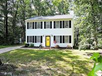 Charming two-story home with black shutters and a bright yellow front door surrounded by lush greenery at 8 Woodsprite Ct, Durham, NC 27703