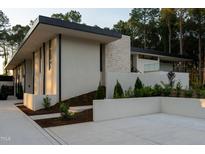 Contemporary home featuring clean lines, a stone accent wall, manicured landscaping and a flat roof design at 812 Stradella Rd, Raleigh, NC 27614
