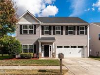 Charming two-story home with a manicured front yard, black shutters, and a two-car garage at 105 Pink Dogwood Ln, Mebane, NC 27302