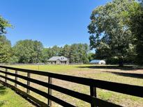 Charming brick home on vast property with a large fenced pasture, under a clear blue sky at 108 Cedarwood Dr, Louisburg, NC 27549