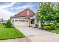 Charming home featuring a tan exterior, attached garage, manicured lawn, and a welcoming front porch at 1096 Aberlour Ln, Burlington, NC 27215