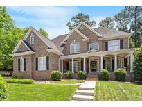 Charming two-story brick home boasts a well-manicured lawn and inviting covered front porch with stately white columns at 117 Arborhill Ln, Holly Springs, NC 27540