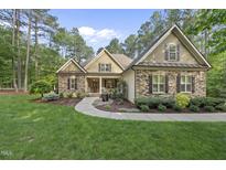 Charming home featuring a stone facade, manicured lawn, and inviting walkway at 1211 New Grissom Way, Wake Forest, NC 27587