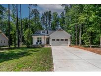Charming single-story white home with a two-car garage and a well-manicured front yard at 136 Hatchet Cv, Louisburg, NC 27549
