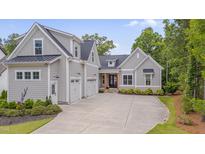 Beautiful gray home with three-car garage, stone pathway, black trim and mature landscaping at 14 Duck Bill Trl, Pittsboro, NC 27312