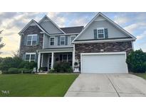 Charming two-story home with stone and siding, lush lawn, and a two-car garage at 30 Sunbury Ct, Zebulon, NC 27597