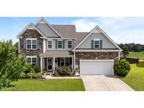 Charming two-story home with a combination of stone and siding, plus a well-manicured lawn and landscaping at 30 Sunbury Ct, Zebulon, NC 27597