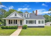 Charming white bungalow featuring a brick chimney and a well-manicured front lawn at 302 Hester St, Knightdale, NC 27545