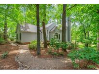 Charming home featuring a stone walkway and lush, mature landscaping, surrounded by mature trees at 304 W Kirkfield Dr, Cary, NC 27518