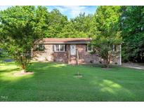 Charming brick home with a lush green front yard and mature trees offering shade at 3329 Broughton Dr, Durham, NC 27704
