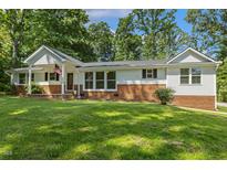 Charming brick and siding home featuring a covered porch and manicured lawn, located in a serene and tree-lined neighborhood at 418 S West St, Cary, NC 27511