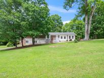 Charming single-story home with a combination brick and white exterior, surrounded by lush trees and a green lawn at 4605 Malor Dr, Wake Forest, NC 27587