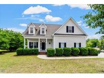 Inviting home showcasing dormer windows and covered front porch at 509 Spruce Meadows Ln, Willow Springs, NC 27592
