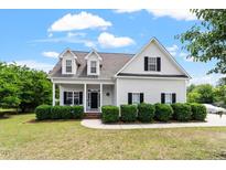 Charming two-story home featuring white siding, black shutters, and a welcoming front porch at 509 Spruce Meadows Ln, Willow Springs, NC 27592