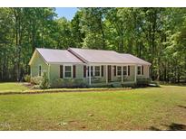 Charming single-story home with a metal roof and covered front porch nestled among trees at 560 Parker Creek Rd, Holly Springs, NC 27540