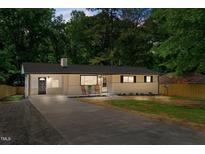 Charming single-story home with a long driveway, rocking chairs, and manicured front yard at 908 W Garden St, Sanford, NC 27330