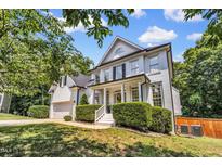 Beautiful two-story home with a charming front porch, lush green lawn and professional landscaping at 1001 Dairy House Ct, Wake Forest, NC 27587