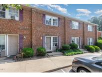 Brick townhome with purple shutters and small shrubs surrounding the front entrance to the property at 103 Coleridge Ct, Carrboro, NC 27510